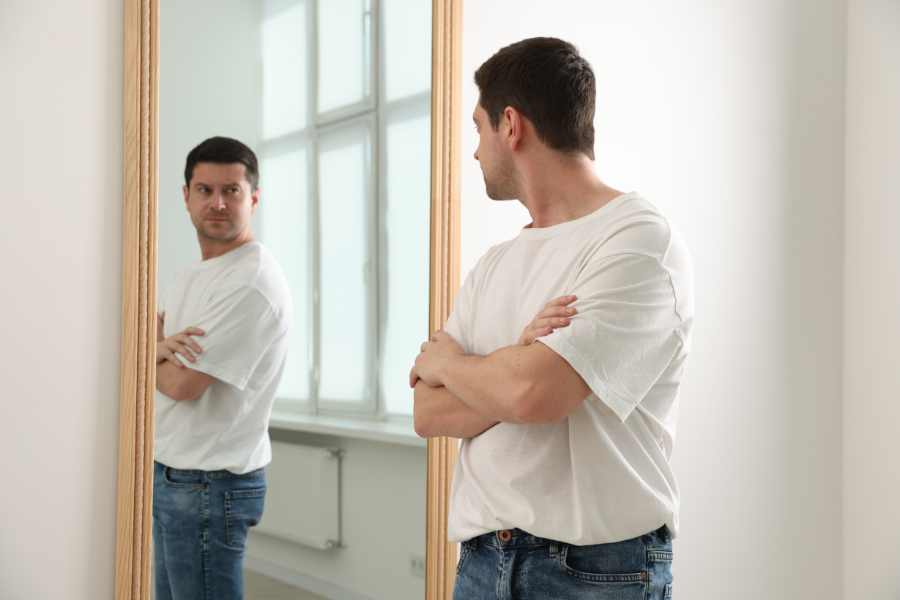 Hombre reflejado en un espejo con rasgos narcisistas